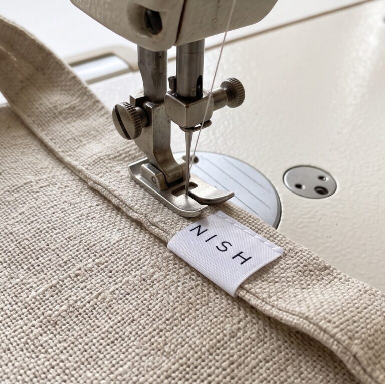 A satin clothing label being sewn on